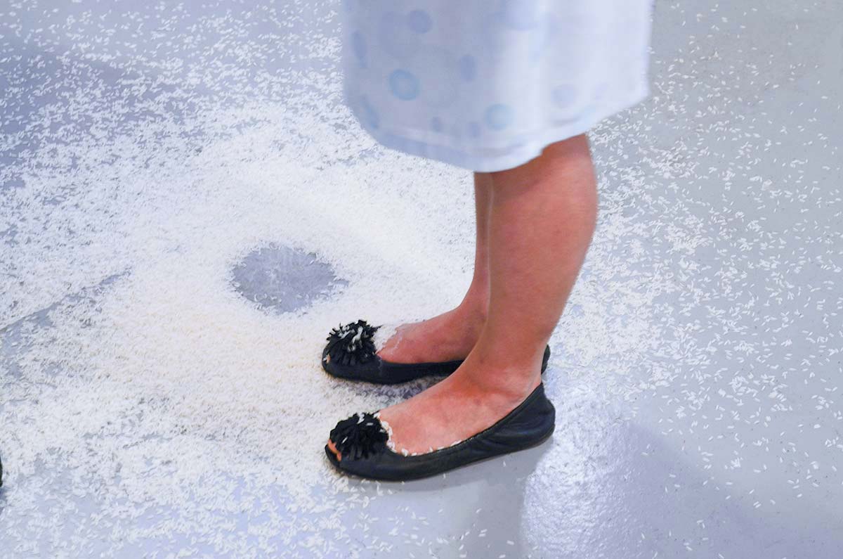 Chun Hua Catherine Dong leaks rice from her bag while having conversation withe people in a gallery in Vancouver. She stops leaking rice when their conversation is over.