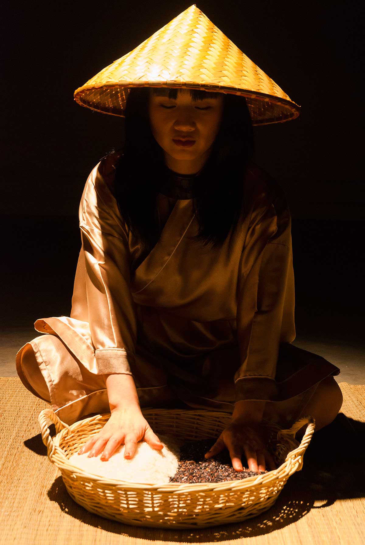 Chun Hua Catherine Dong closes her eyes, sits on a mat and gently touches the black and white rice in front of her, she is ready to perform her rice performance