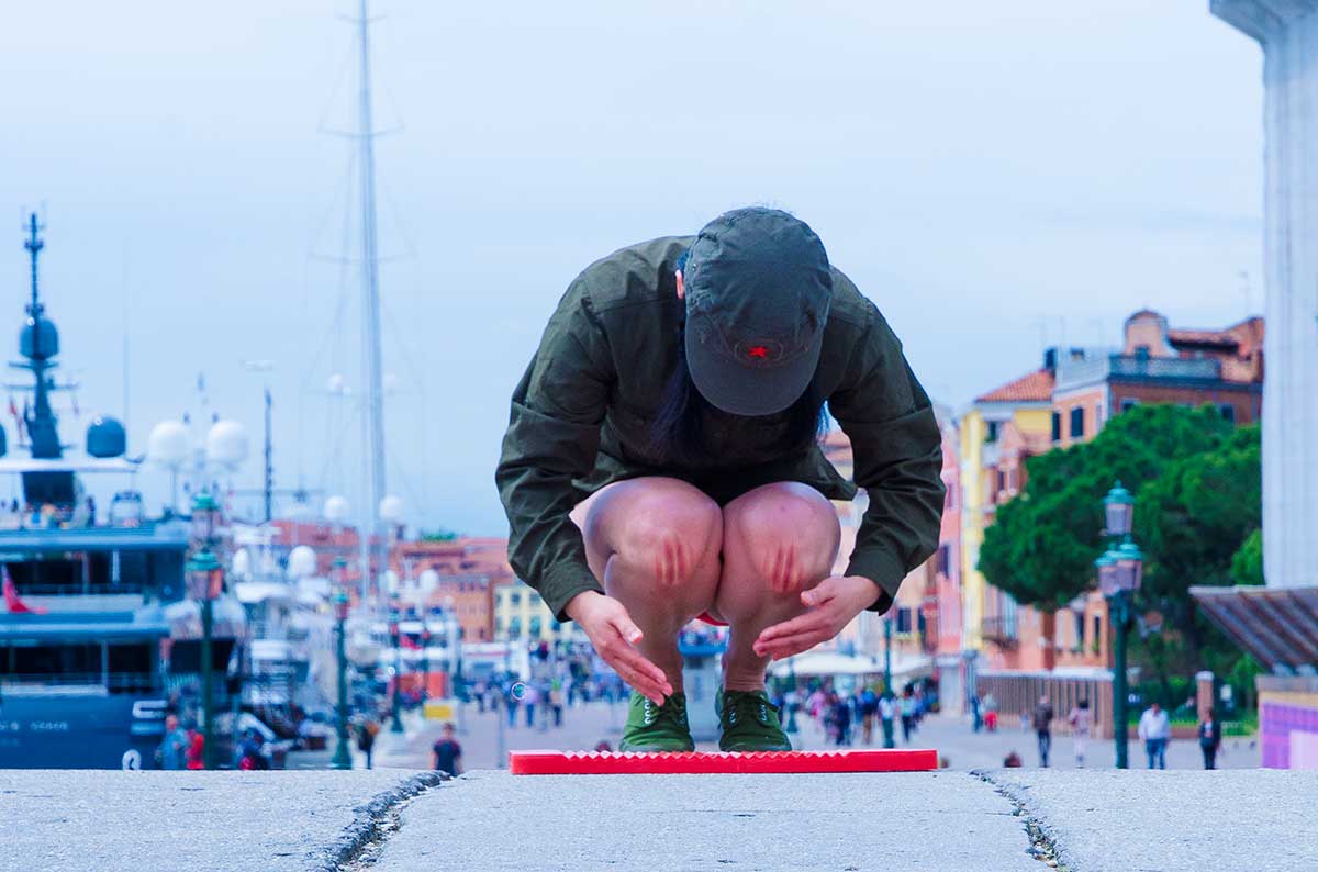 Chun Hua Catherine Dong wear a military suit and red underwear, kneeling on a washboard and keeping straight and still as long as she can in Venice Biennale in 2013