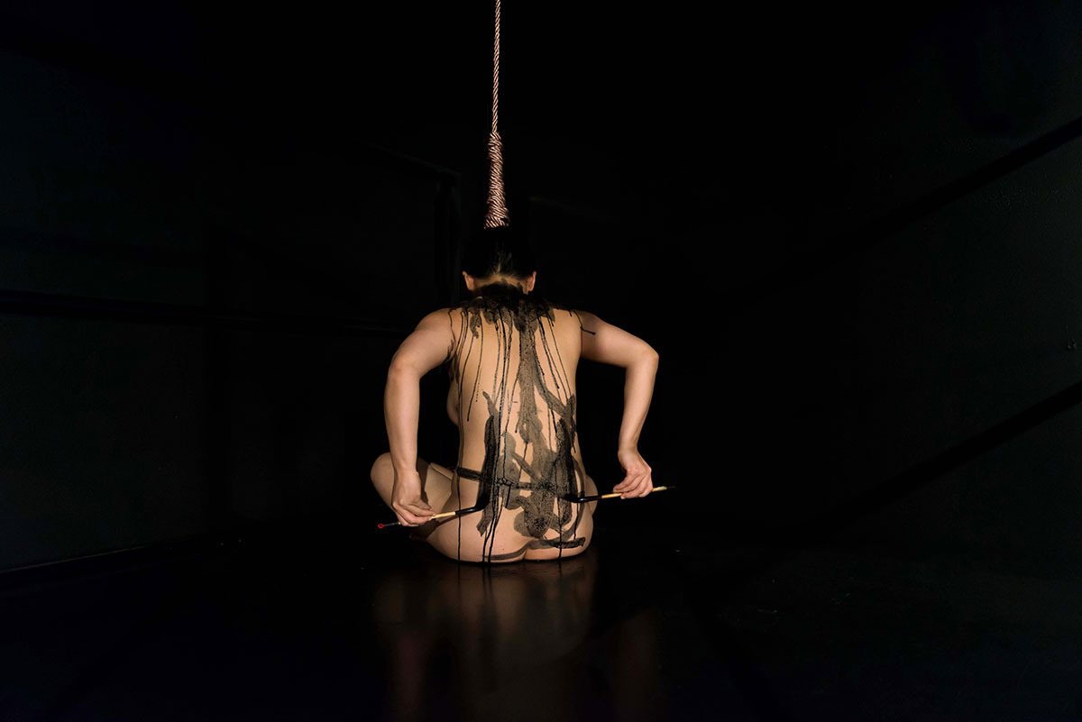 Chun Hua Catherine Dong is naked, hanging her hair with a rope on ceiling, using ink to write on her back  
