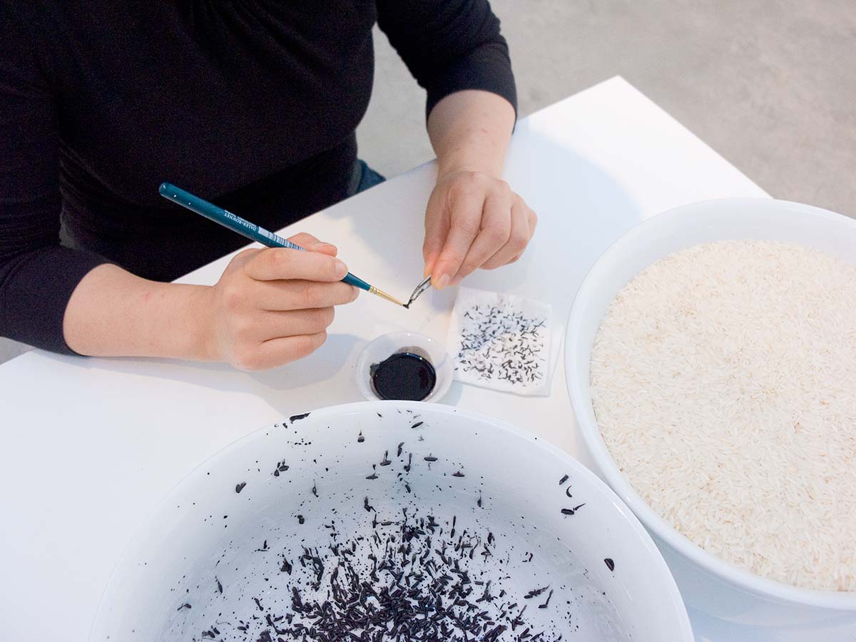 Chun Hua Catherine Dong paints rice with black ink in her performance in Vancouver, she wants amount of rice in two bowls are equal