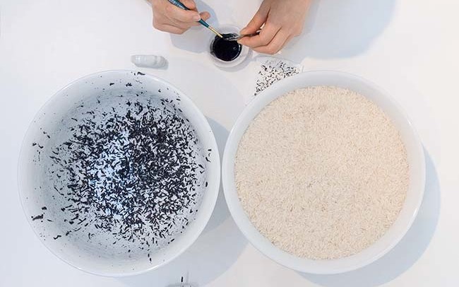 Chun Hua Catherine Dong paints rice with black ink and invites audiences to paint the rice with her and chat