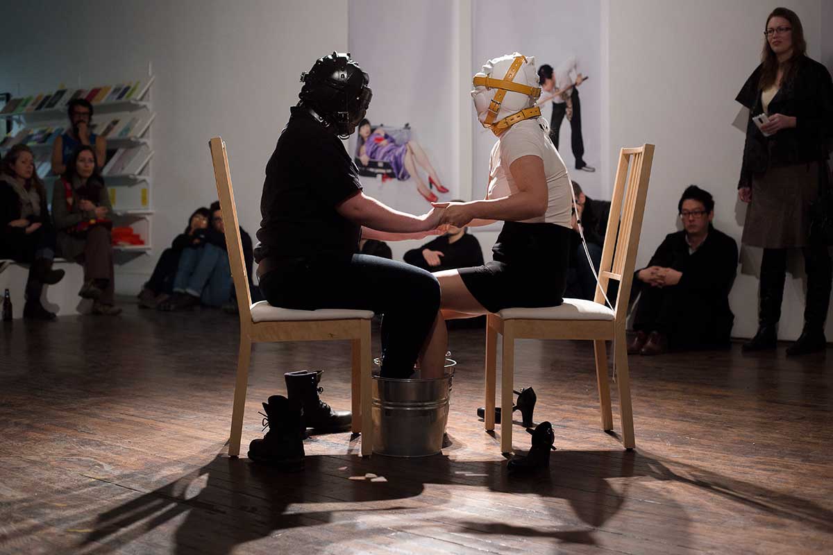 Chun Hua Catherine Dong performs at Articule Montreal: two girls wear masks and put their feet on two buckets, which one is filled with ice, another one is filled with boiled water