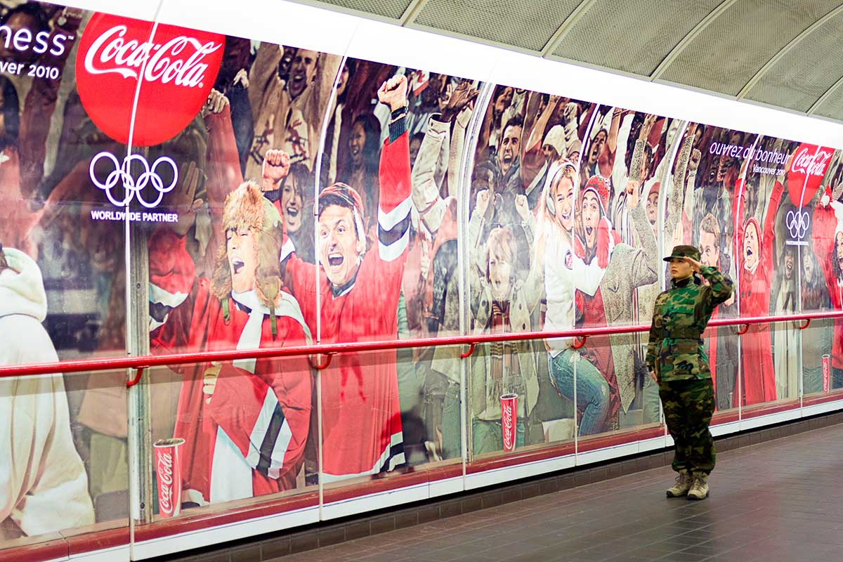 Chun Hua Catherine Dong wears military suit and salutes with her left hand, a wrong hand, to Olympic advertisement during Vancouver 2010 Winter Olympics