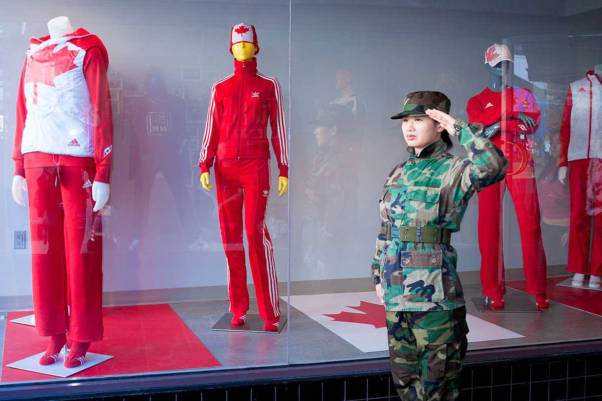 Chun Hua Catherine Dong wears military suit and salutes with her left hand, a wrong hand, to Olympic symbols during Vancouver 2010 Winter Olympics