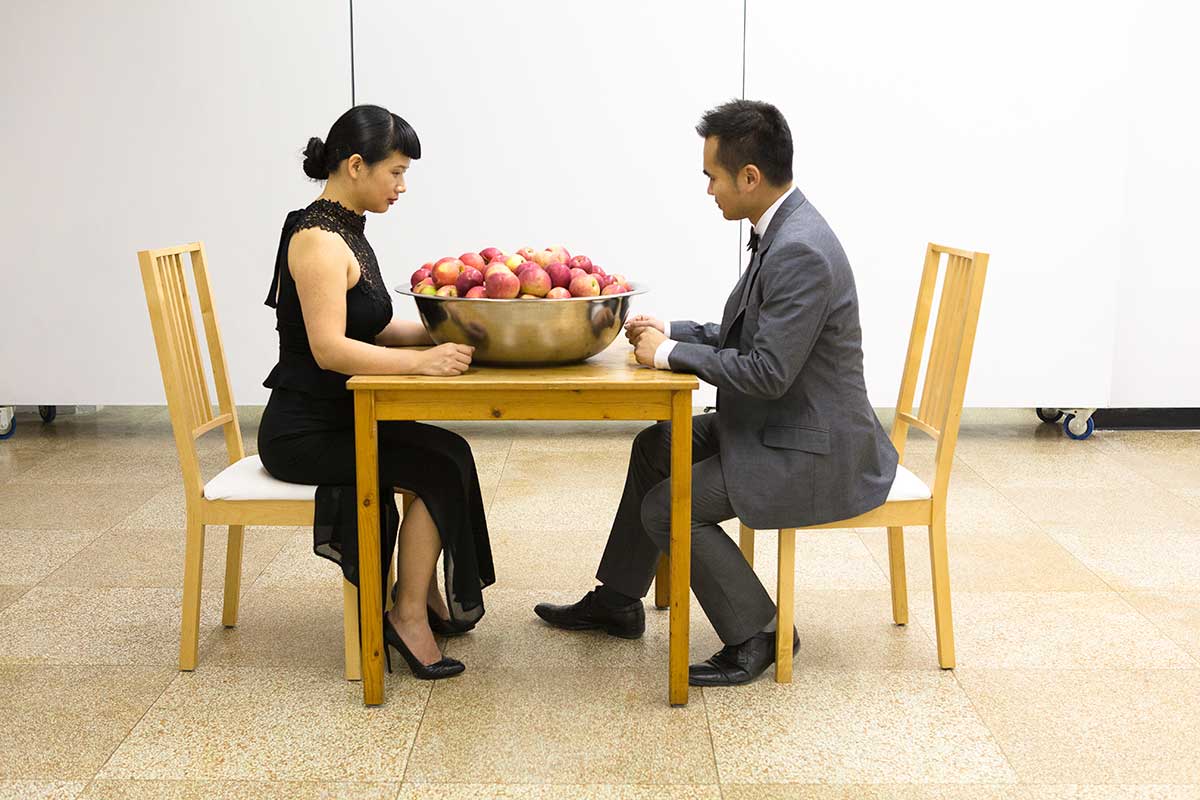 Chun Hua Catherine Dong and her performance partner sit facing each other, looking at apples, they are ready to make some actions