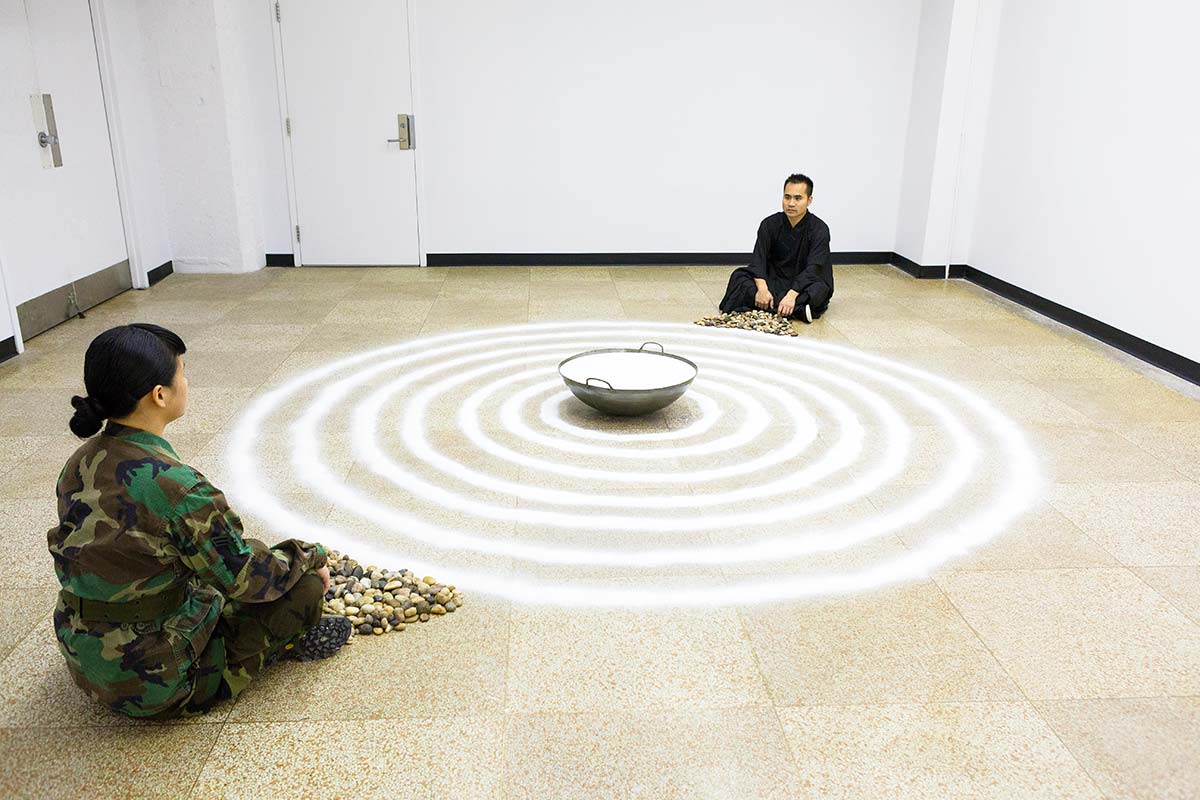 Chun Hua Catherine Dong and a monk meditate in front of seven circles that was made with salt