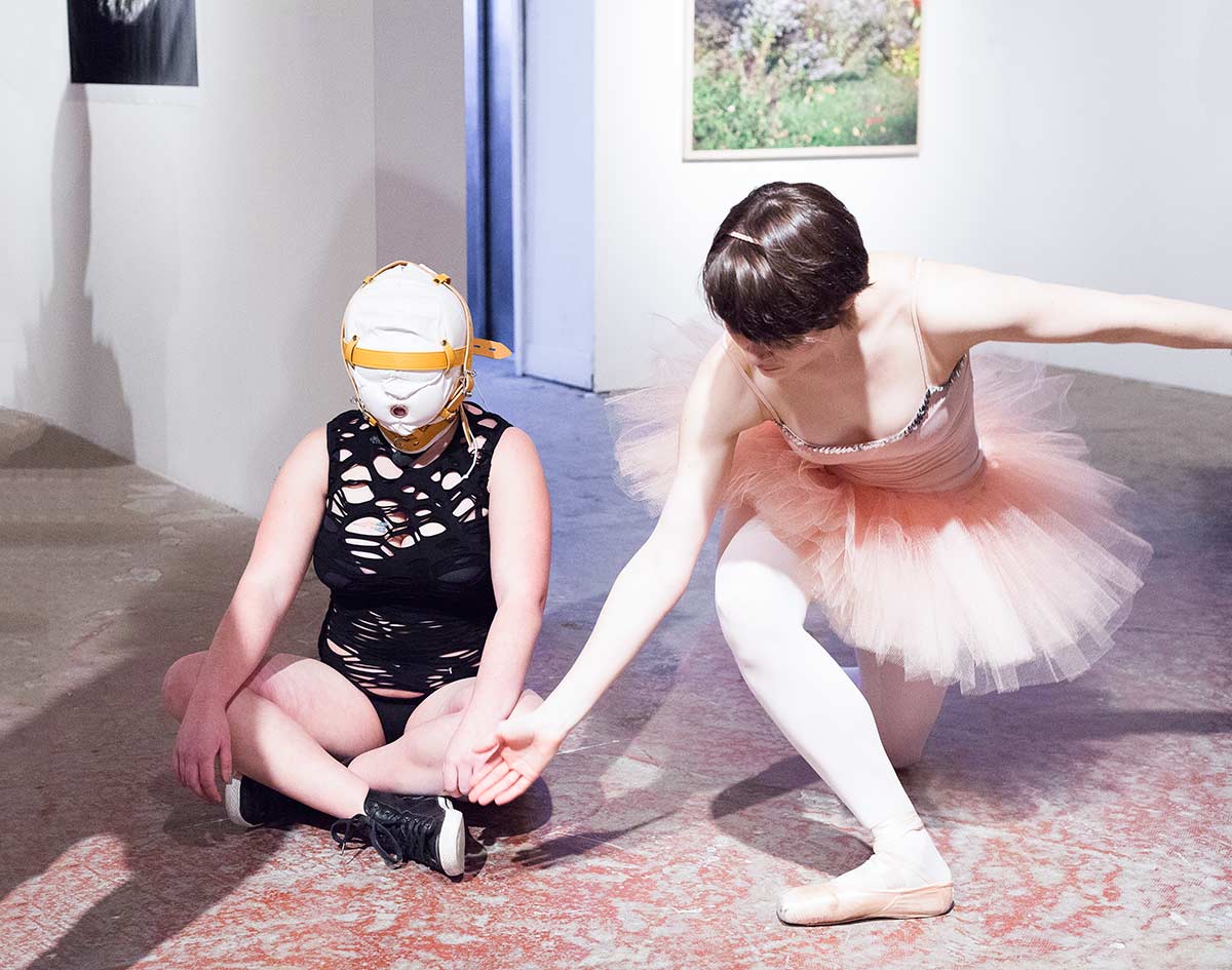 Chun Hua Catherine Dong invited a ballerina, a dominatrix, and a monk to improvise a performance at an exhibition opening in Montreal. the ballerina is trying to hold the dominated girl's hand