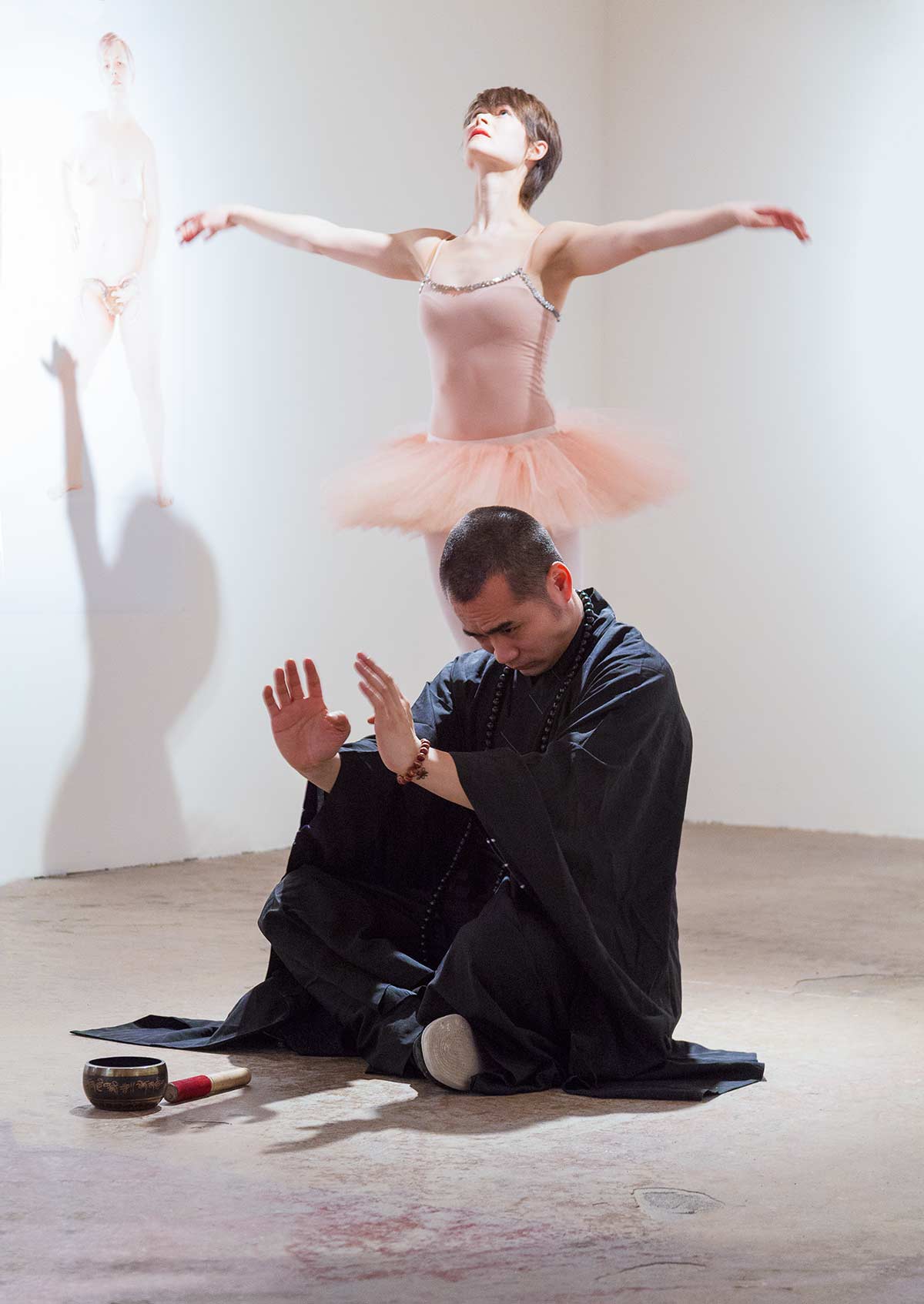 Chun Hua Catherine Dong invited a ballerina, a dominatrix, and a monk to improvise a performance at an exhibition opening in Montreal. the ballerina is dancing while the monk is meditating  