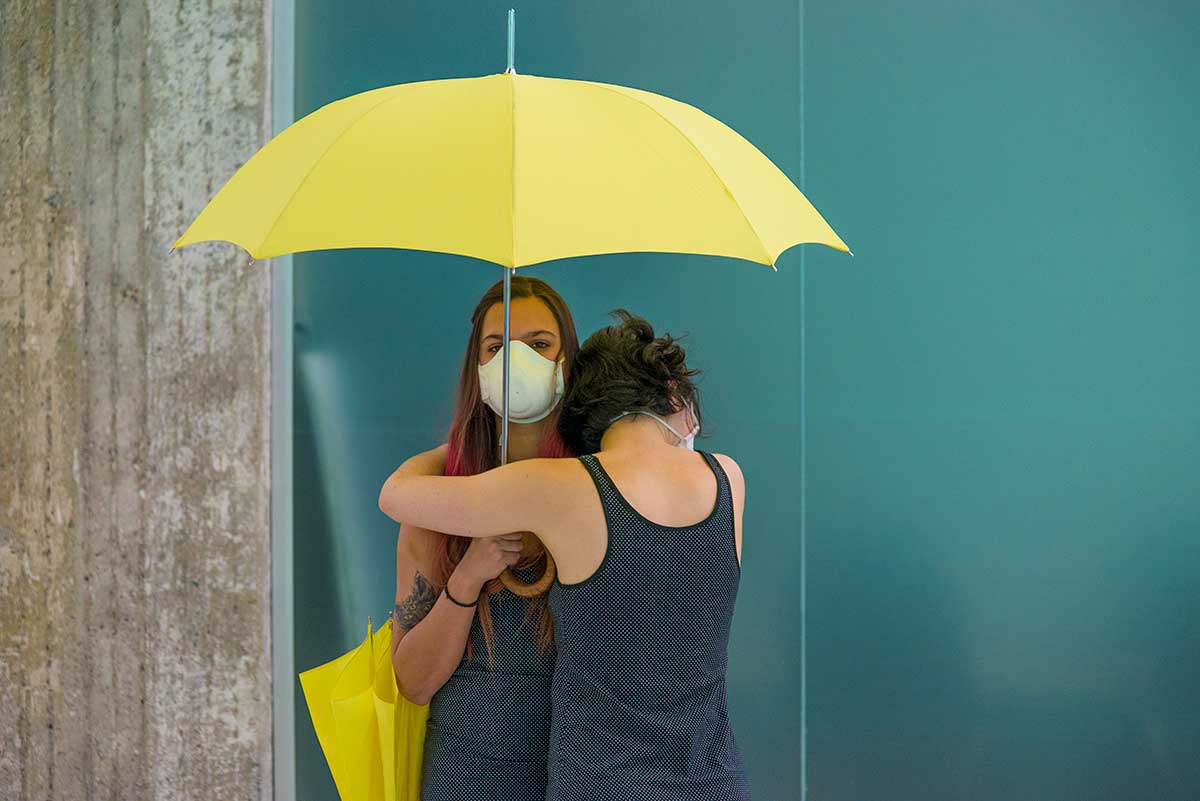 Chun Hua Catherine Dong's Yellow Umbrella performance: 2 females hold yellow umbrellas and hug each other