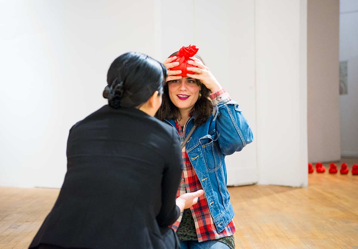 an audience is participating Chun Hua Catherine Dong's performance at her solo exhibition opening at aceartinc in Winnipeg 2016