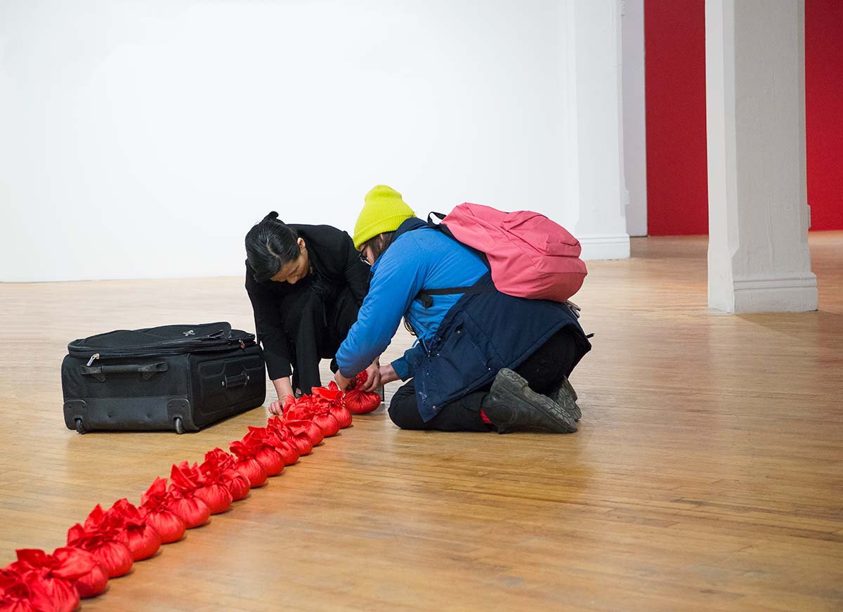 an audience is participating Chun Hua Catherine Dong's performance at her solo exhibition opening at aceartinc in Winnipeg 2016