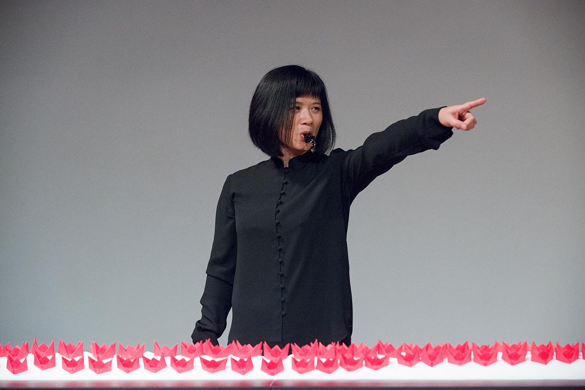 Chun Hua Catherine Dong's performance at 7a11d International Festival of Performance Art in 2016: Dong points to audiences and have a whistle in her mouth.