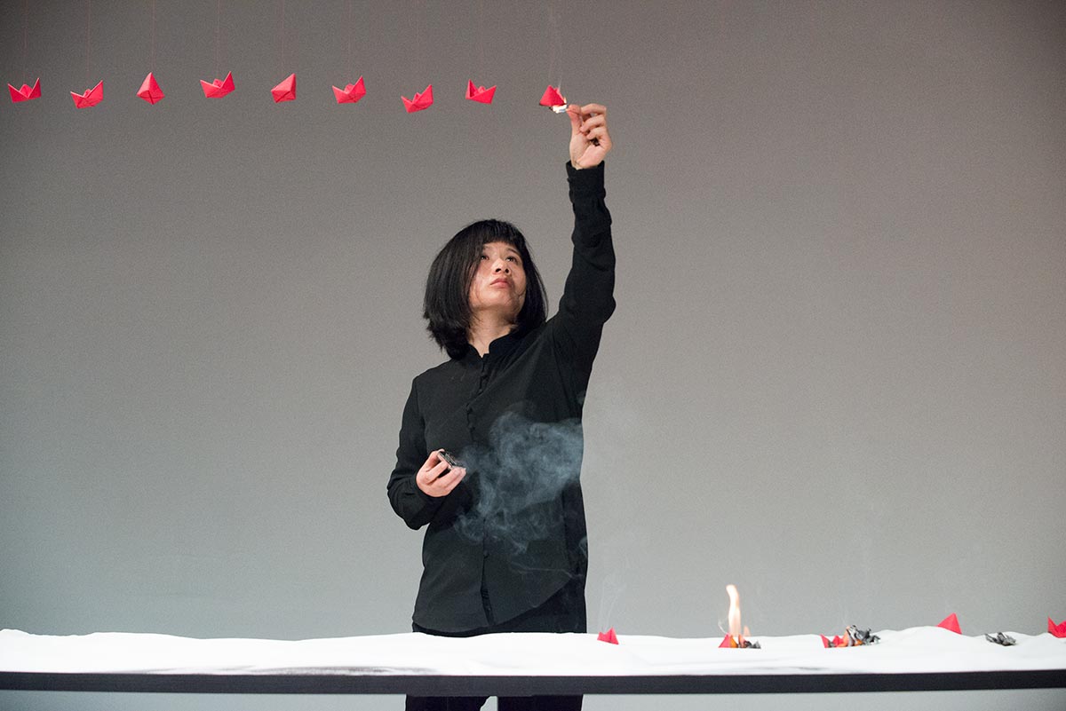 Chun Hua Catherine Dong's performance at 7a11d International Festival of Performance Art in 2016: Dong burns red paper boats on the celling