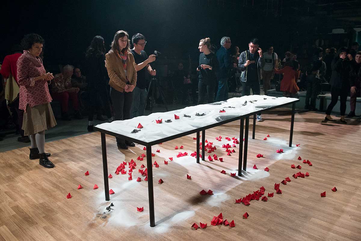 Chun Hua Catherine Dong's performance at 7a11d International Festival of Performance Art in 2016: audiences closely examine Dong's performance, Dong gives paper boats to the audiences. 