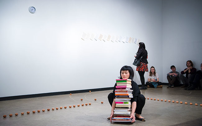 Chun Hua Catherine Dong tries to stand up while she is holding a stack of books