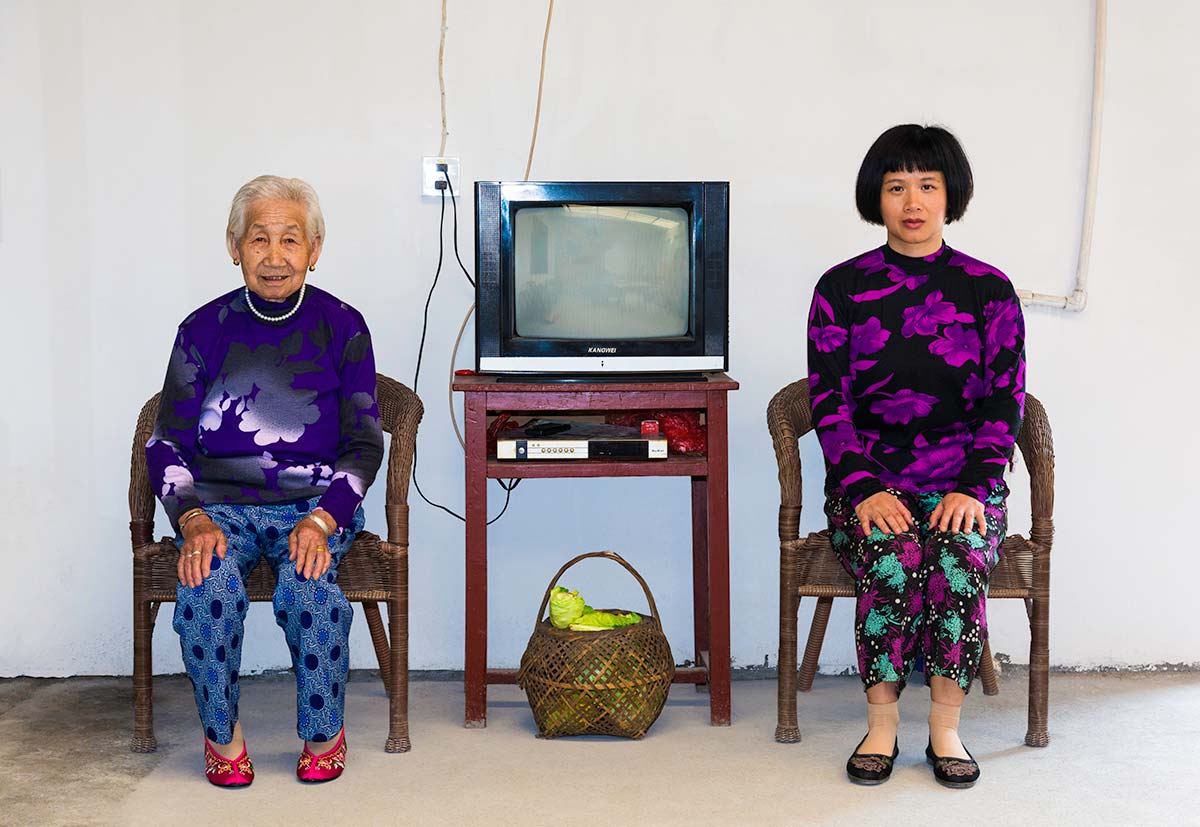 Chun Hua Catherine Dong and a mother sit beside a table, their postures mirror each other