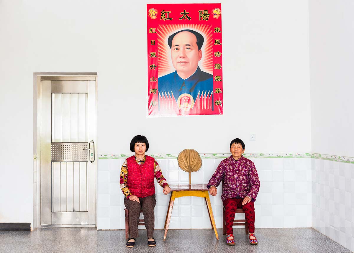 Chun Hua Catherine Dong and a mother sit beside a table, their postures mirror each other