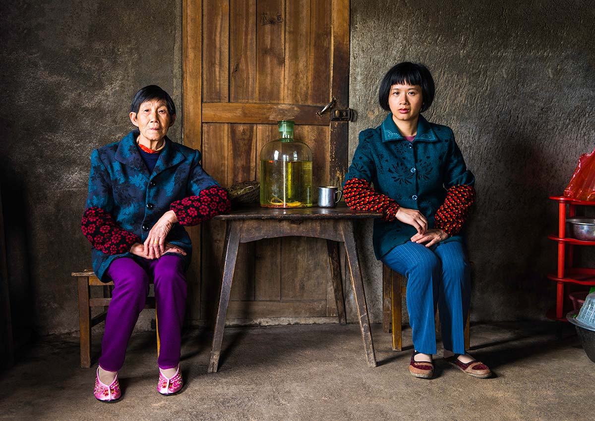 Chun Hua Catherine Dong and a mother sit beside a table, their postures mirror each other