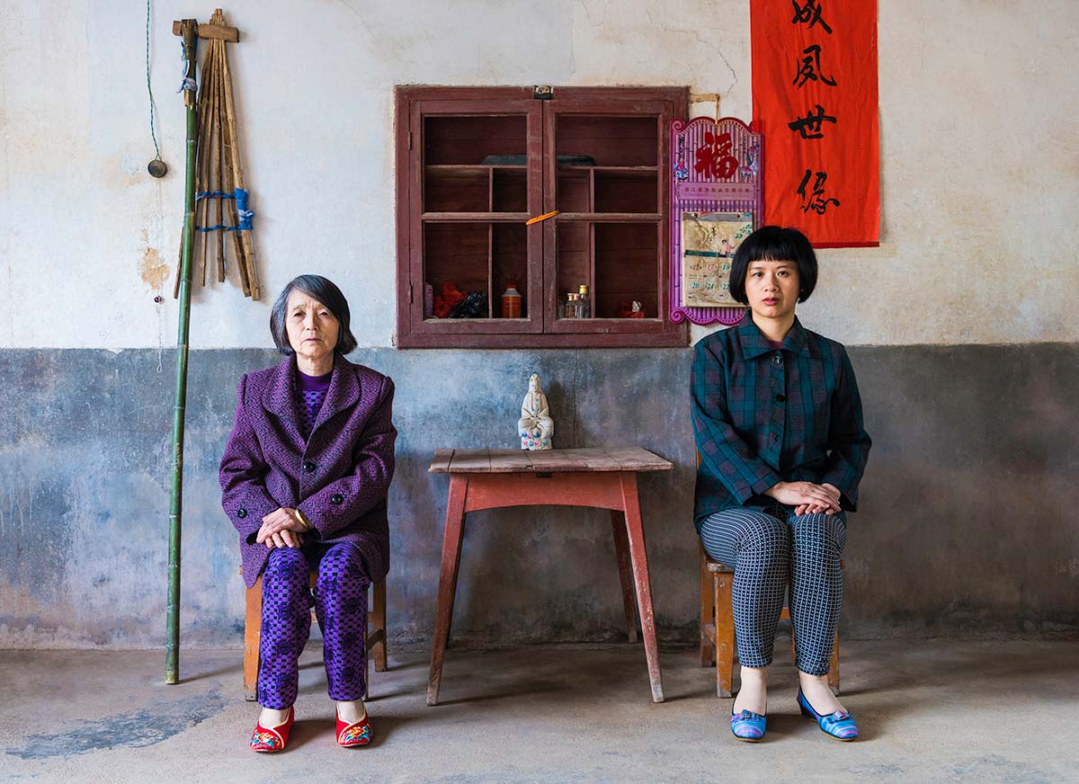 Chun Hua Catherine Dong and a mother sit beside a table, their postures mirror each other