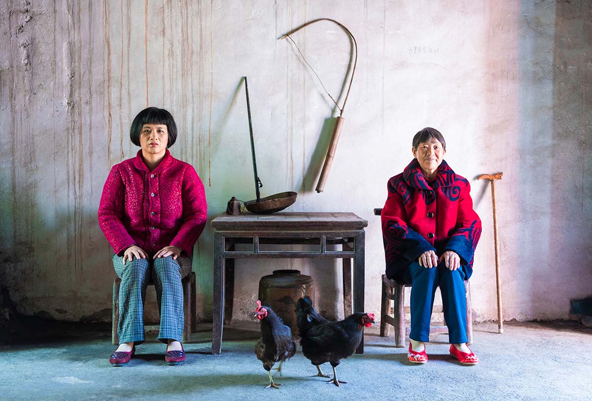 Chun Hua Catherine Dong and a mother sit beside a table, their postures mirror each other