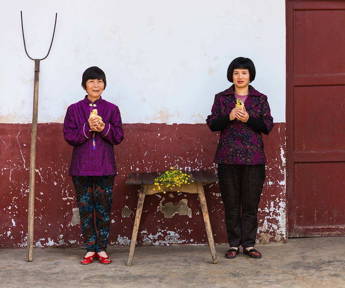 Chun Hua Catherine Dong and a mother sit beside a table, their postures mirror each other