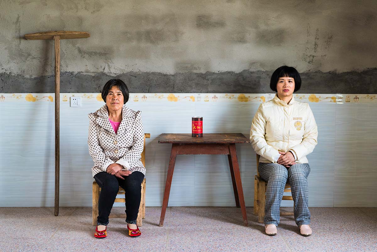 Chun Hua Catherine Dong and a mother sit beside a table, their postures mirror each other