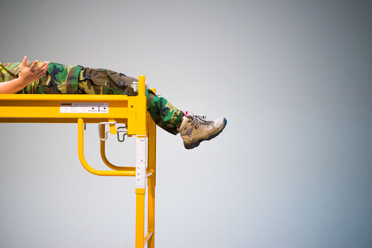 Chun Hua Catherine Dong wears military suit, lying on a scaffold 