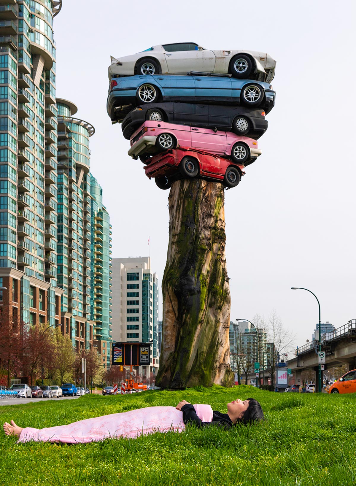 Chun Hua Catherine Dong lies under a fake tree with cars on top in Vancouver 