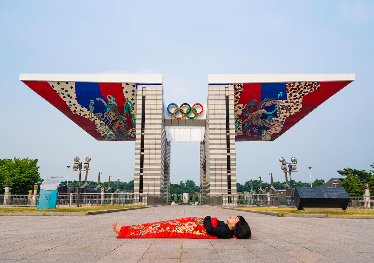 Chun Hua Catherine Dong buries herself with her red corpus cover at Olympic Park in Seoul