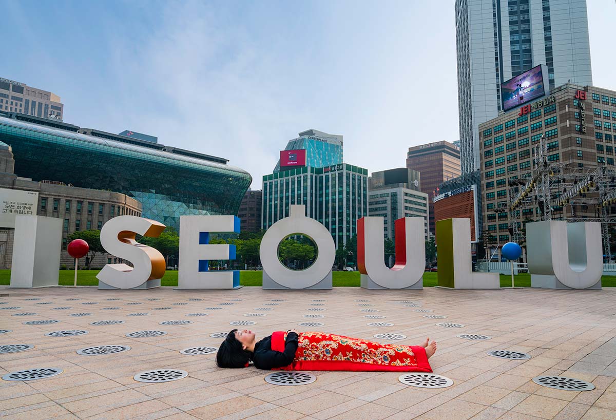 Chun Hua Catherine Dong buries herself with her red corpus cover at the City Hall  in from of I SEOUL U in Seoul