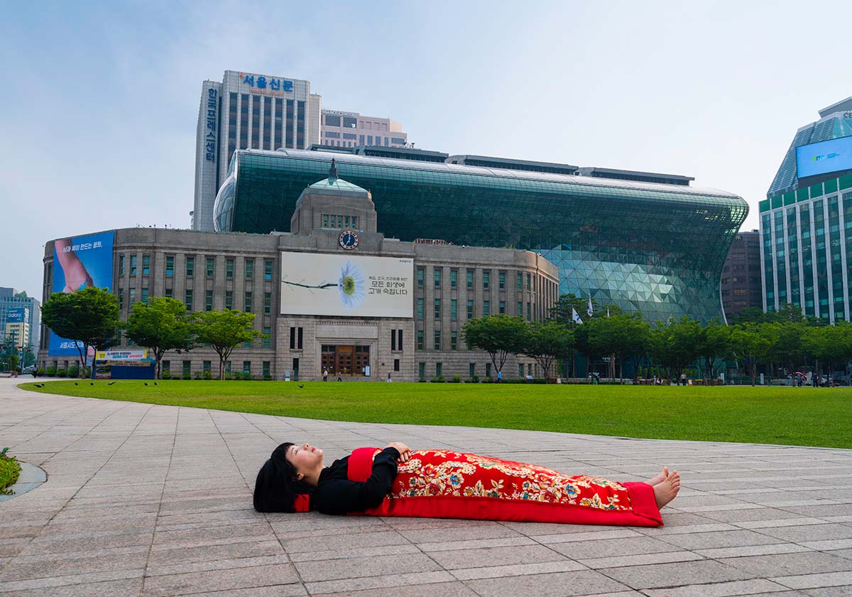 Chun Hua Catherine Dong buries herself with her red corpus cover at the City Hall  in Seoul