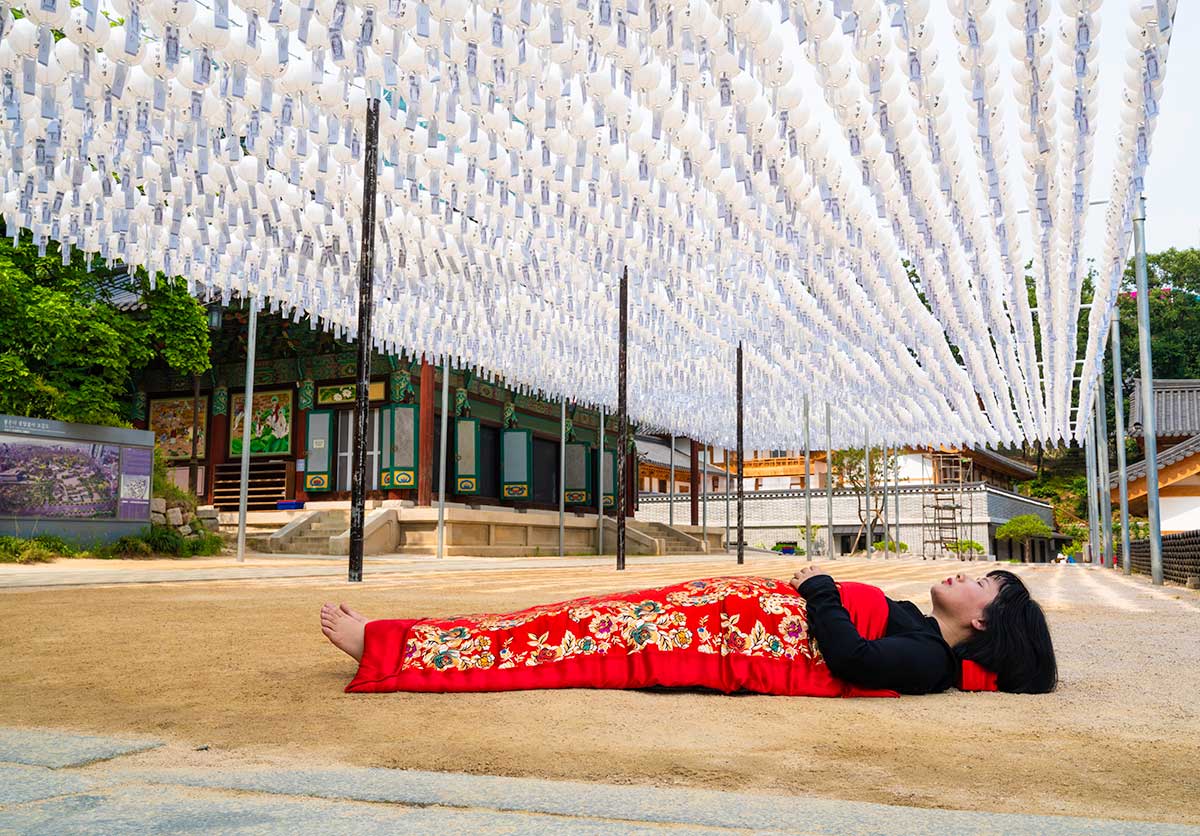 Chun Hua Catherine Dong buries herself with her red corpus cover at Bongeunsa Buddhist Temple in Seoul