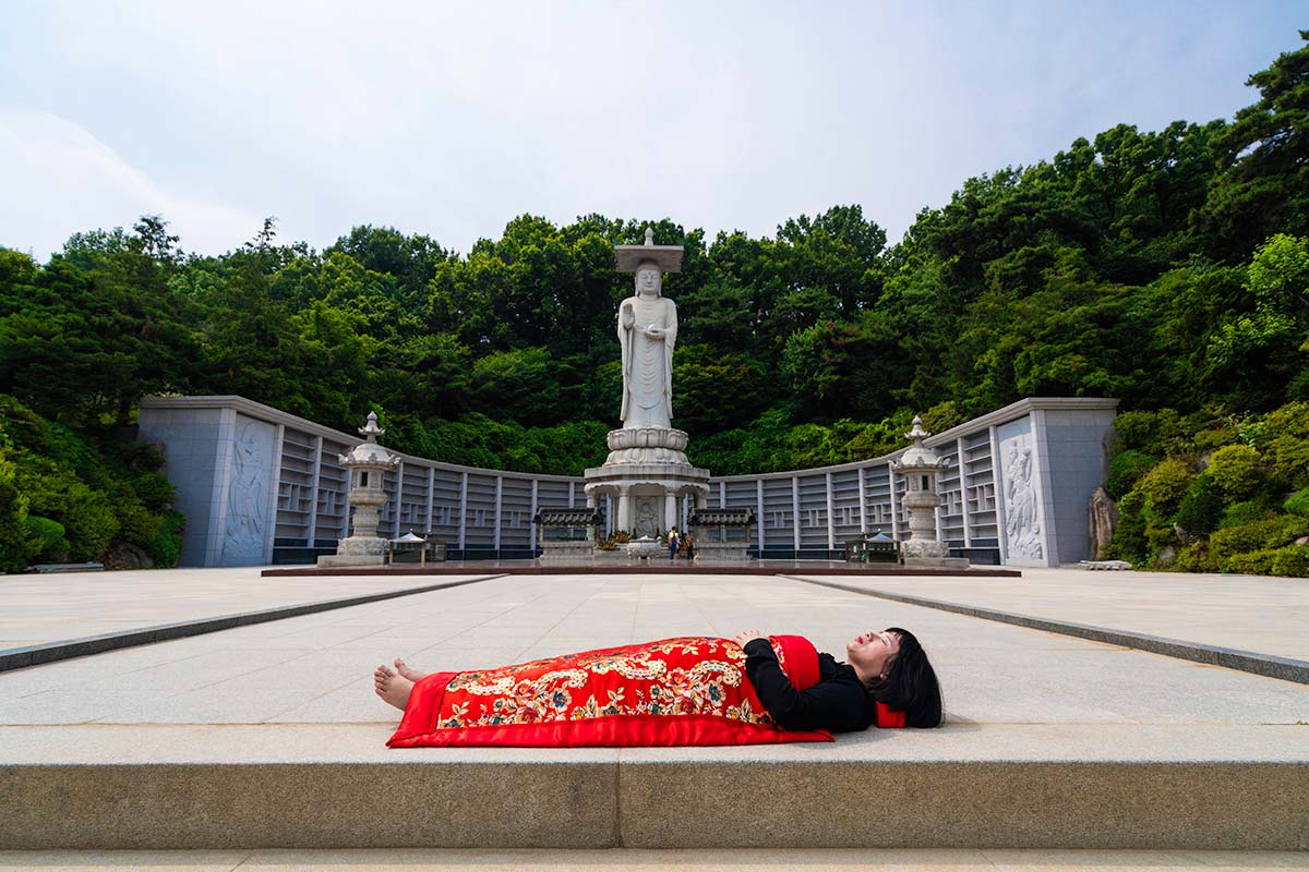 Chun Hua Catherine Dong buries herself with her red corpus cover at Bongeunsa Buddhist Temple in Seoul