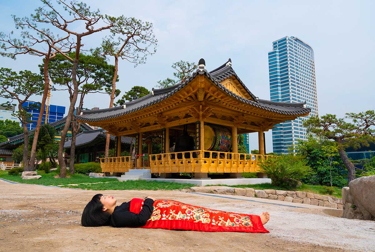 Chun Hua Catherine Dong buries herself with her red corpus cover at Bongeunsa Buddhist Temple in Seoul