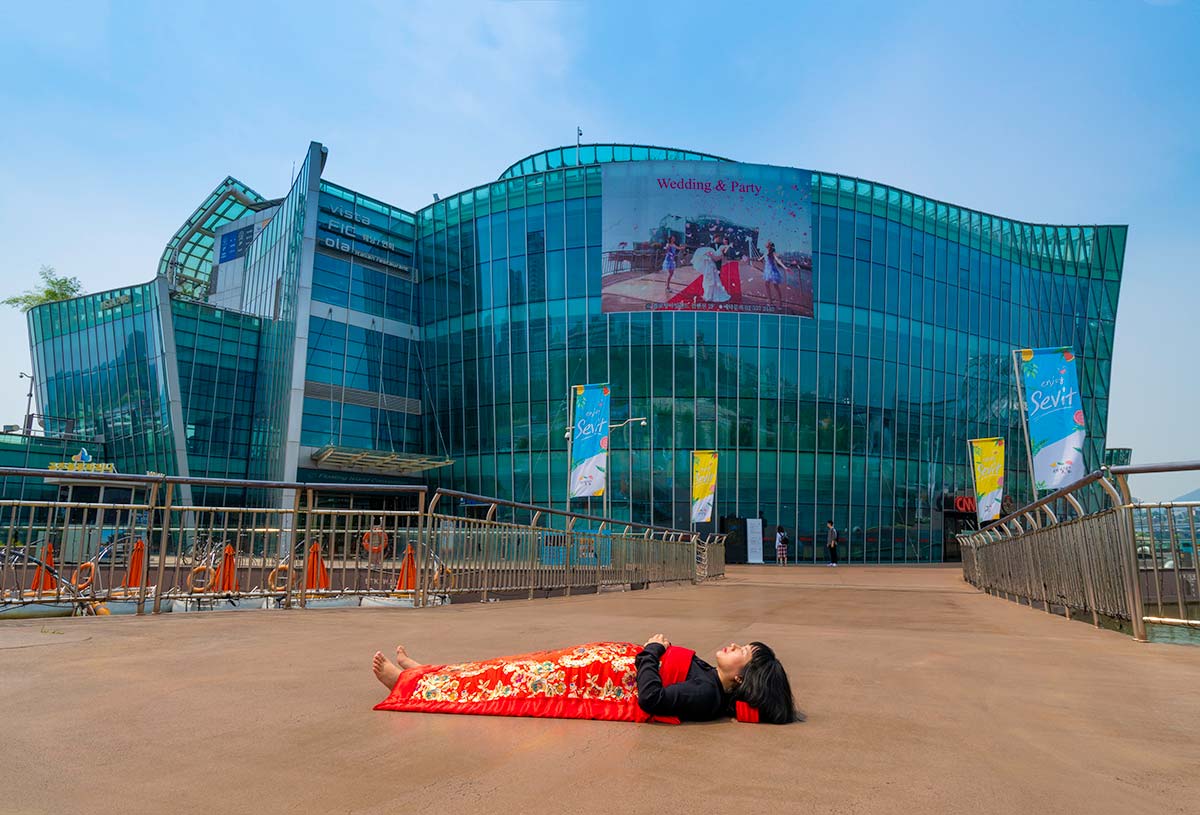 Chun Hua Catherine Dong buries herself with her red corpus cover at The Floating Islands in Seoul