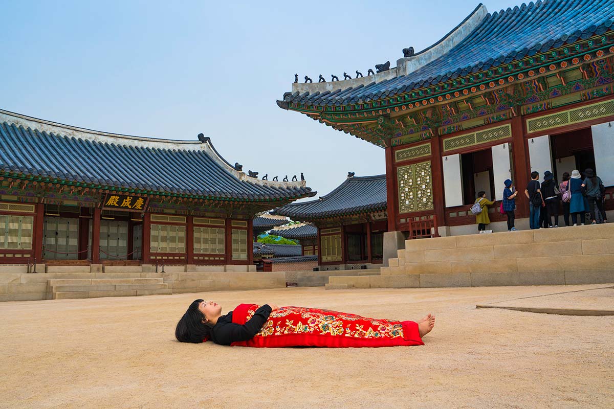 Chun Hua Catherine Dong buries herself with her red corpus cover at Gyeongbokgung Palace in Seoul