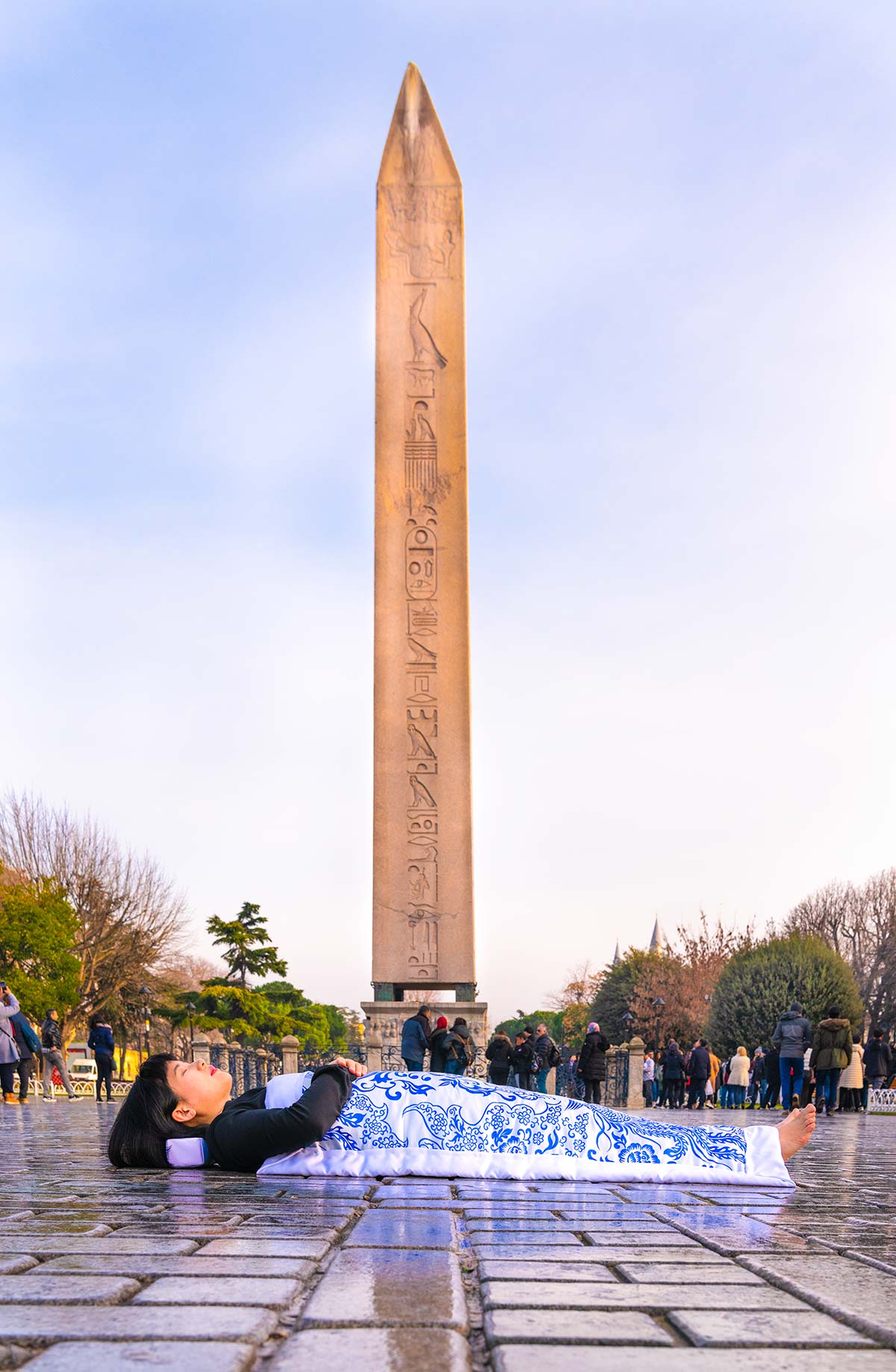 Chun Hua Catherine Dong covers herself with a duvet and performs death ritual  in front of Obelisk of Theodosius in Istanbul