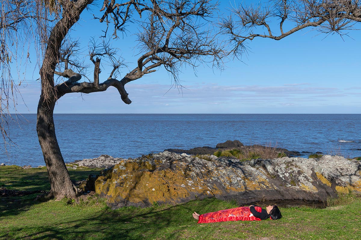 Chun Hua Catherine Dong sleeps under a tree on ocean in Colonia del Sacramento, Uruguay