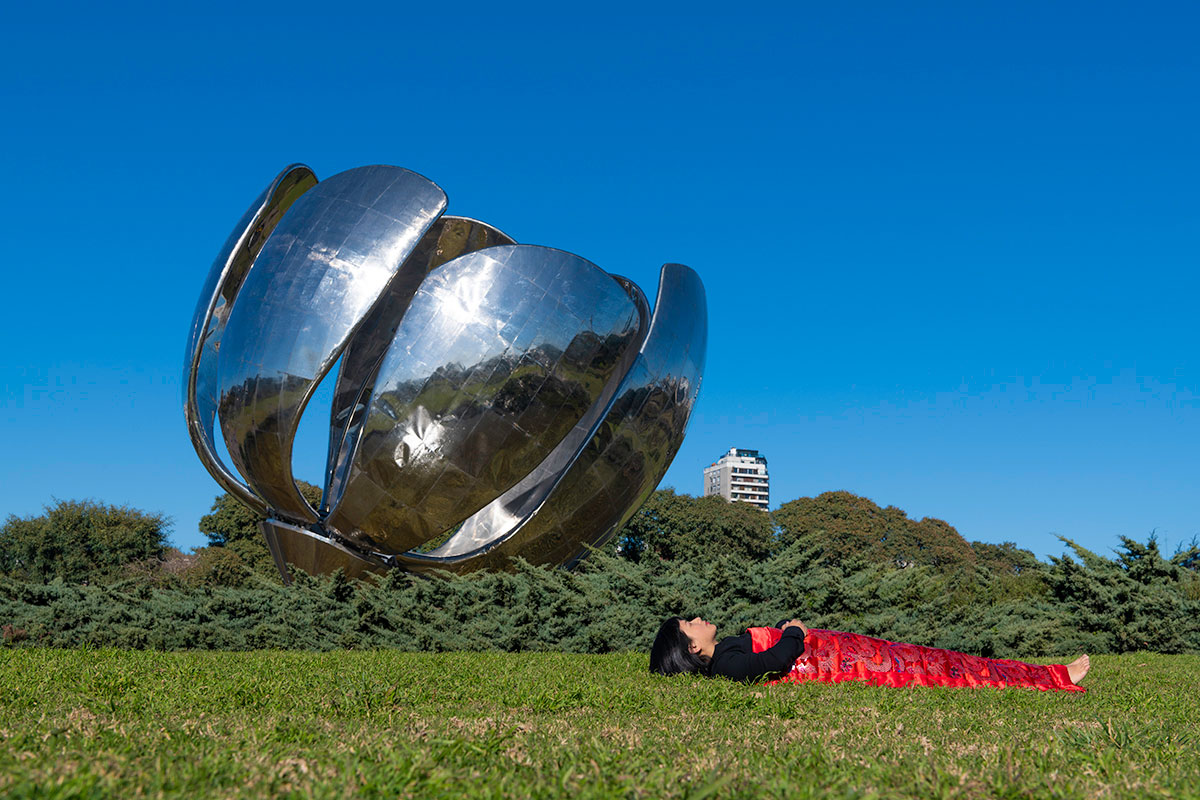 Chun Hua Catherine Dong sleeps under a metal flower, Floralis Genérica, Buenos Aires