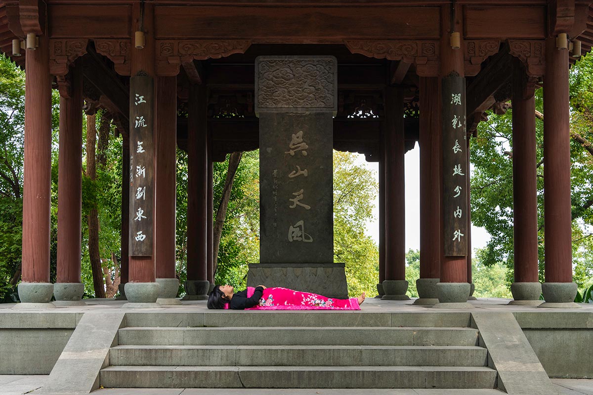 Chun Hua Catherine Dong sleeps in front of a tomb in HangZhou, China 