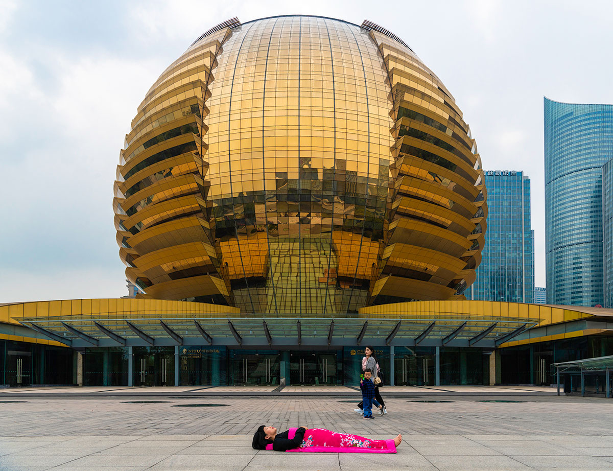 Chun Hua Catherine Dong sleeps in front of a big golden ball in HangZhou, China 