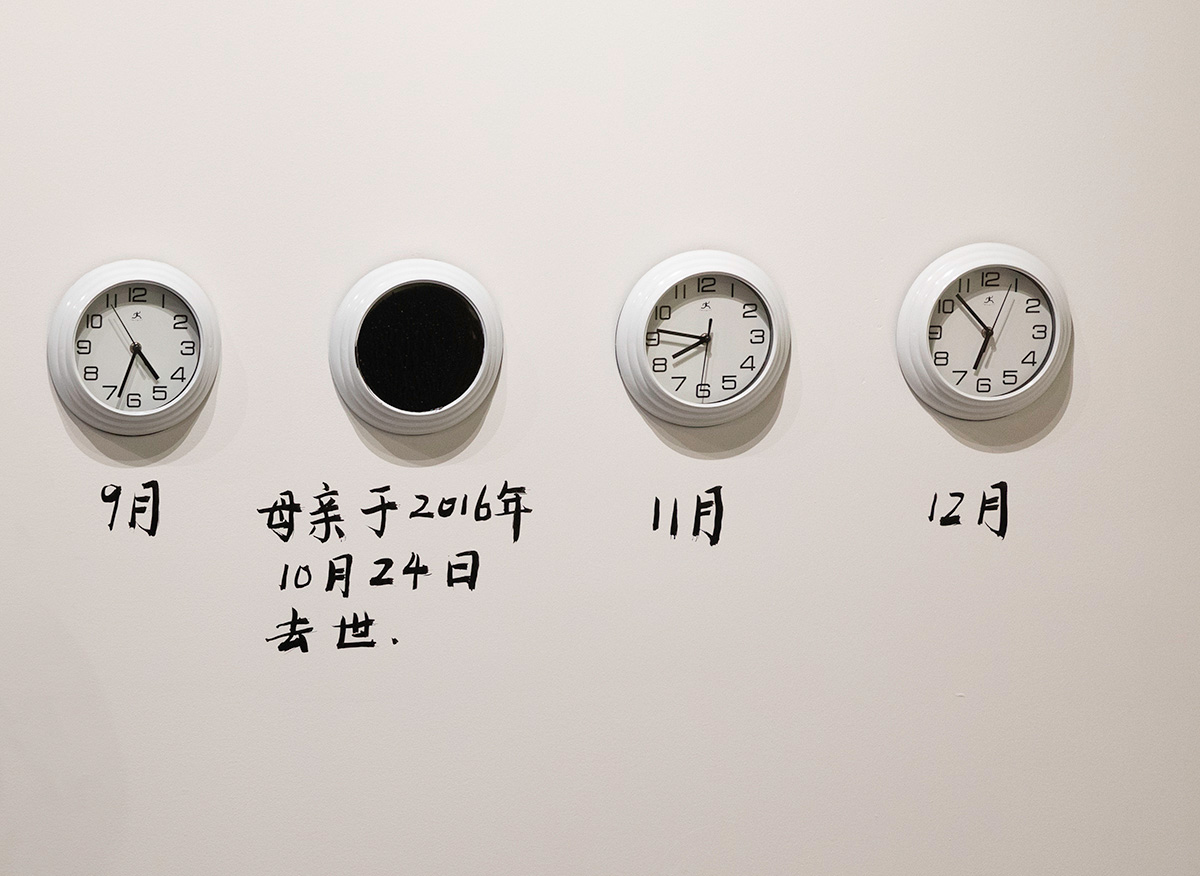 Chun Hua Catherine Dong uses ink to block a clock at Neutral Ground Gallery