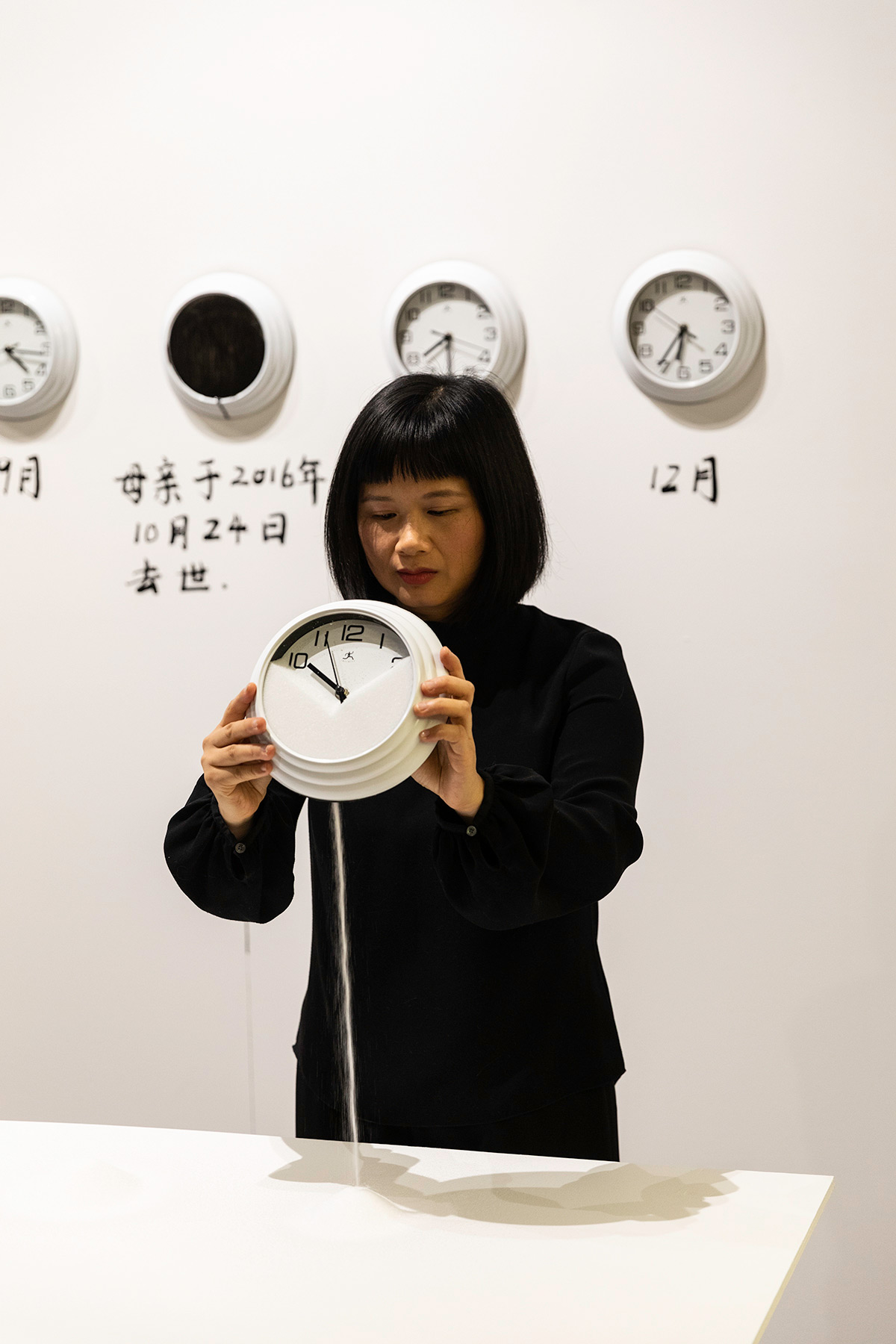 Chun Hua Catherine Dong lets salt run from a clock at Neutral Ground Gallery