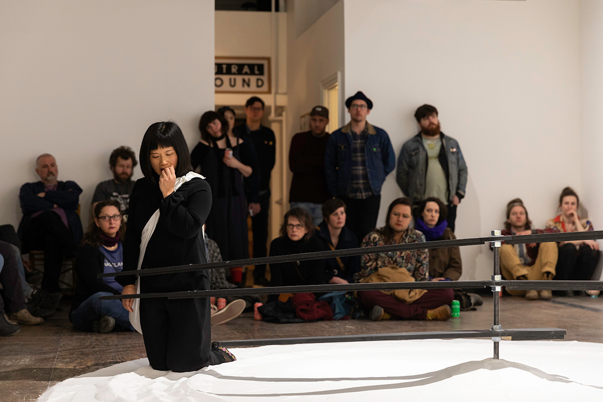 Chun Hua Catherine Dong kneels on salt and walk with the clock backwards at Neutral Ground Gallery