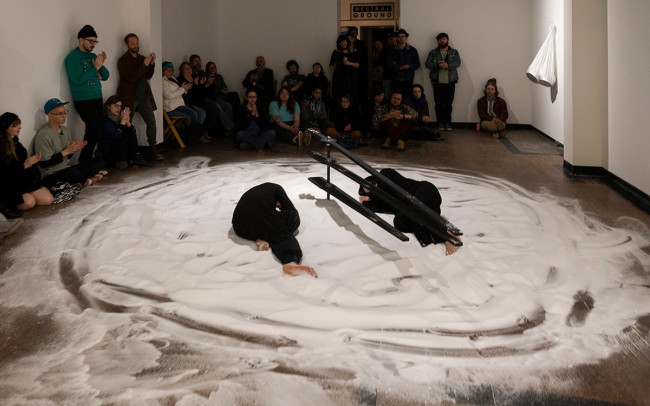 Chun Hua Catherine Dong and her dancer partner sleep on salt clock and look at each other at Neutral Ground Gallery