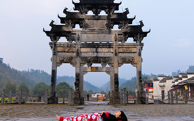 Chun Hua Catherine Dong celebrates her death and sleeps in front of an old monument in HuangSha, China