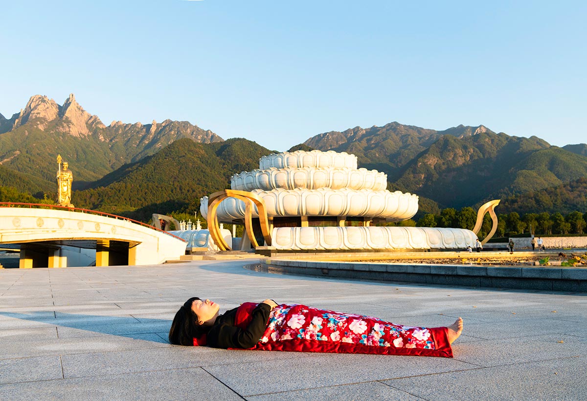 Chun Hua Catherine Dong celebrates her death and sleeps in front of big lotus flower in HuangShan, China