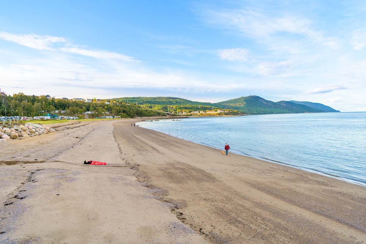 a girl is covered by a red blanket and lies beside Saint Lawrence River