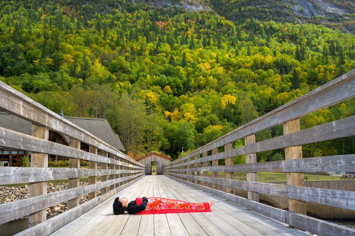 a girl is covered by a red blanket and lies on bridge